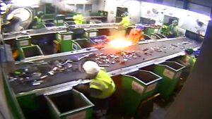 Recycling operatives in a MRF sorting cabin taking cover as a battery explodes on a conveyor belt.