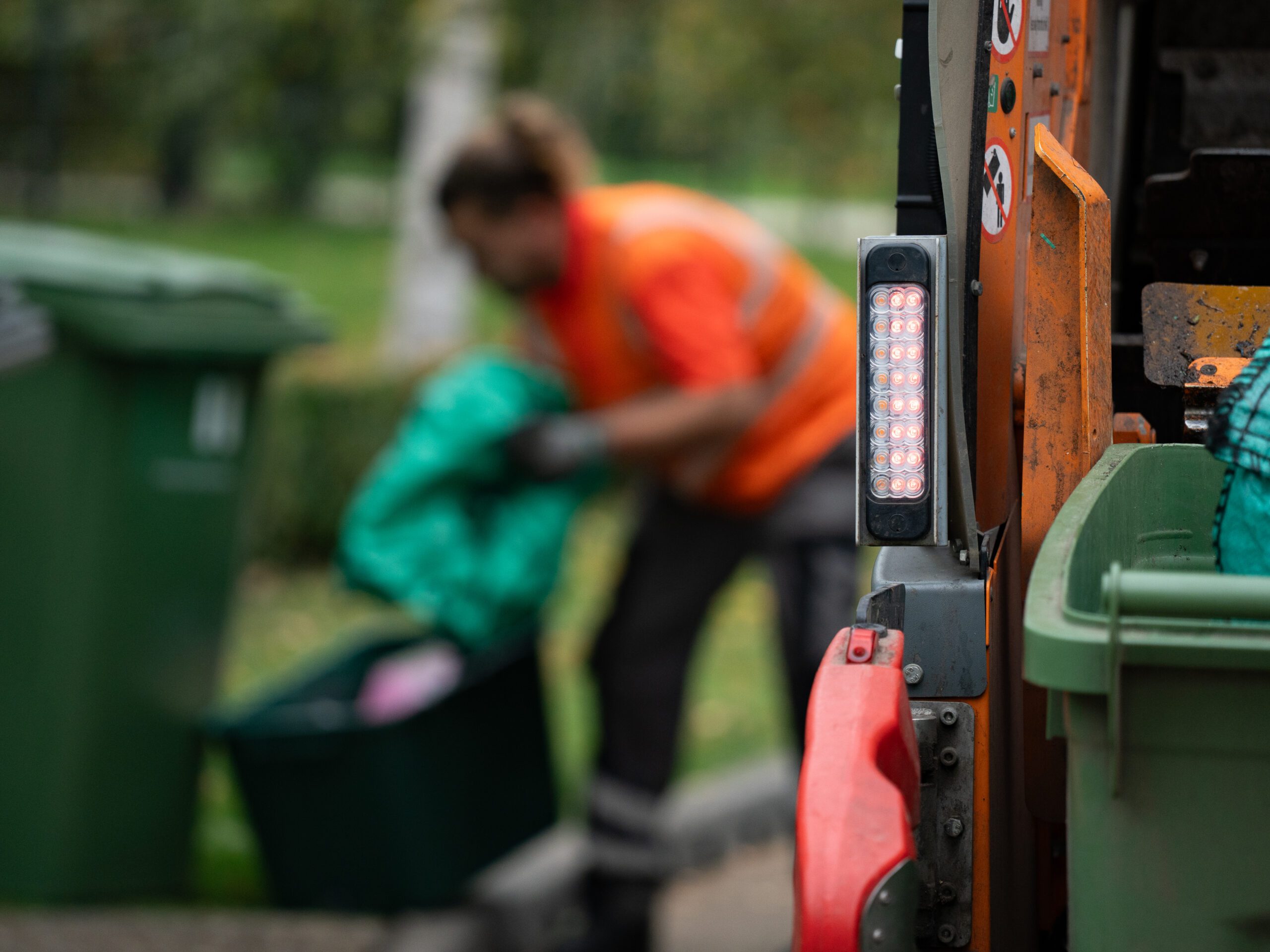 Operative in orange high-vis collects recycling at the kerbside